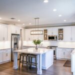 Elegant white kitchen featuring an island, modern appliances, and ample natural light.